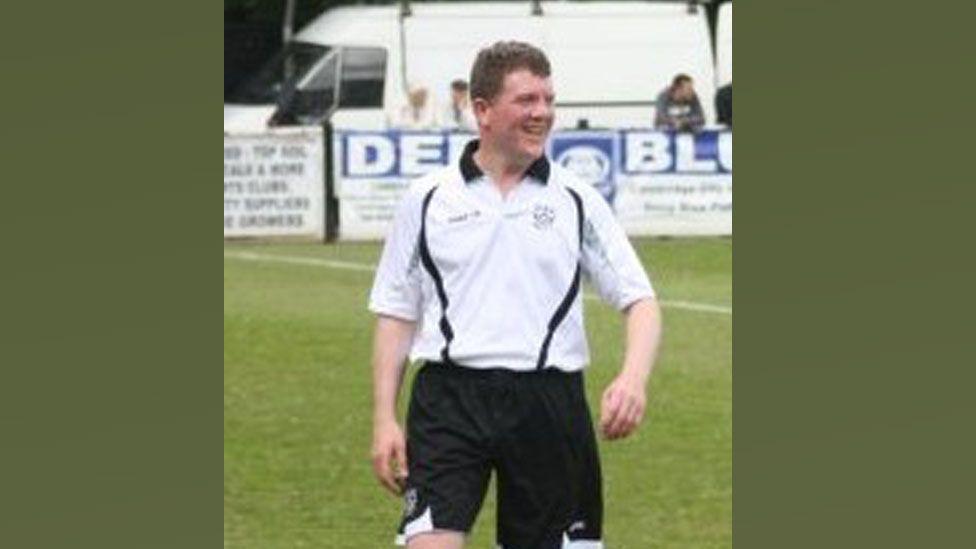 A blurry image of Neil Harvey in black and white football strip on the Milton Road pitch. He is looking towards the left and smiling. It was taken during a Cambridge City 'Legends' against BBC Radio Cambridgeshire at Milton Road in May 2010