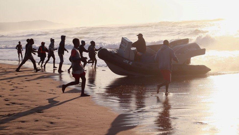 Fisherman run across a beach in Scottburgh, South Africa on 12 June.