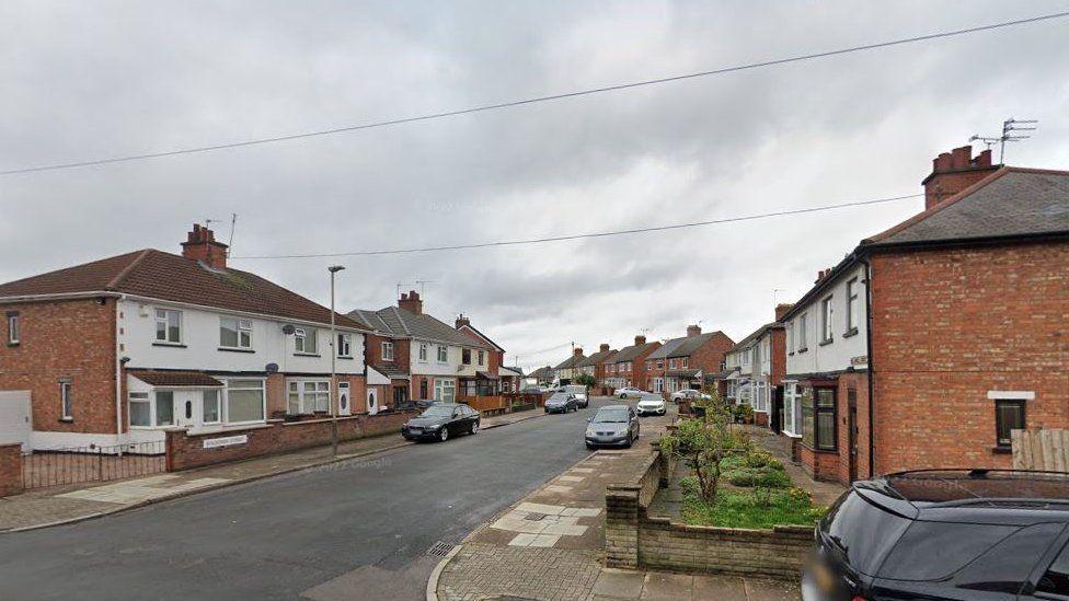 A street level view of a suburban residential road with two-storey semi detached houses.