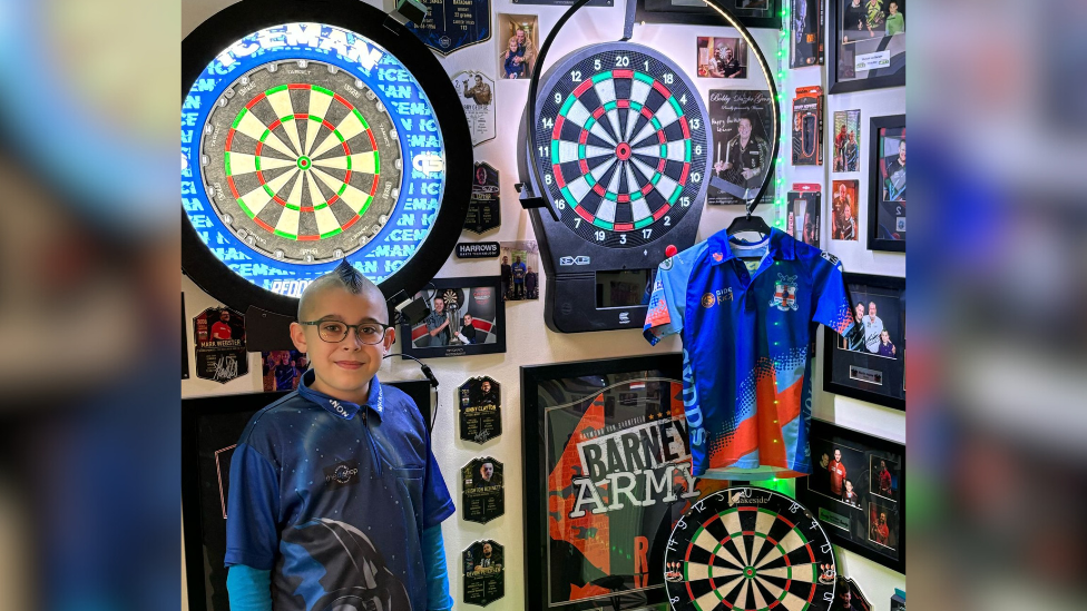 Lennon Wharf surrounded by darts merchandise, including three boards