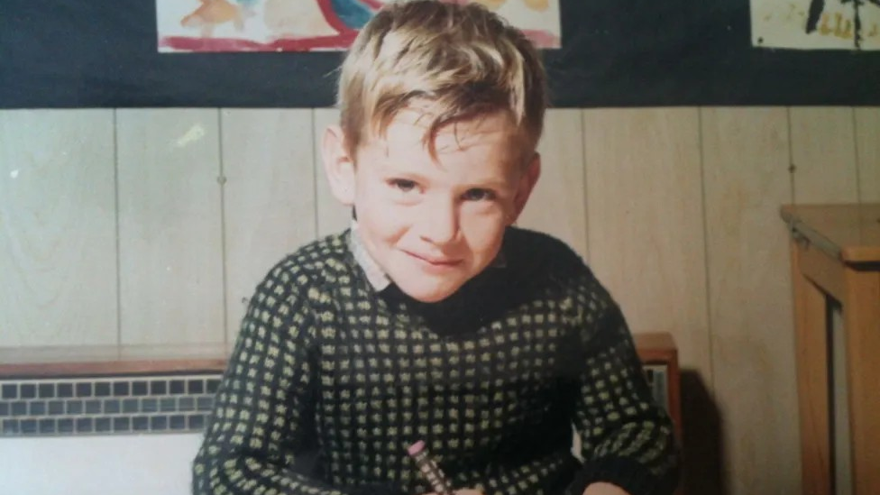 Ian Walden as a small boy, drawing with crayons on paper.