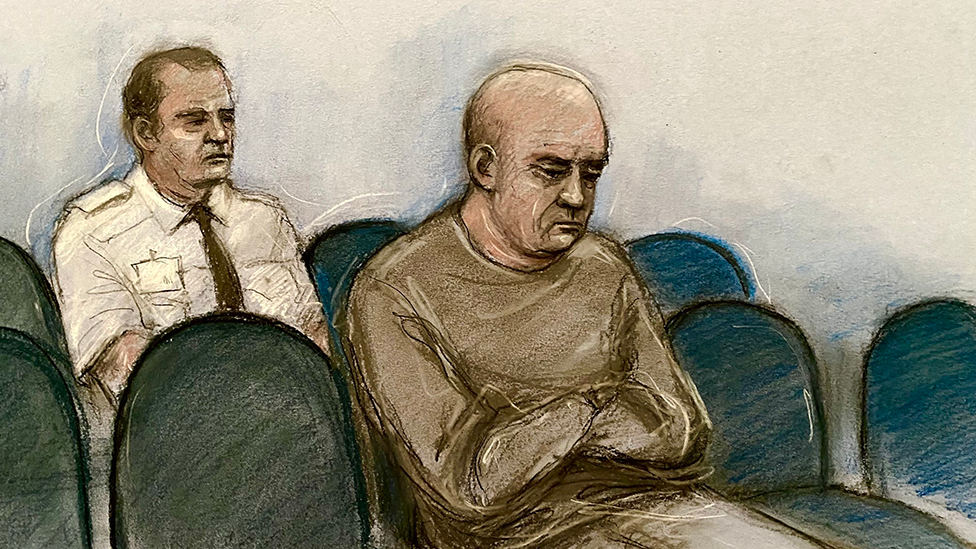 A court drawing of a man in a dark brown jumper sitting in the dock with a court officer in a white shirt and dark tie behind him