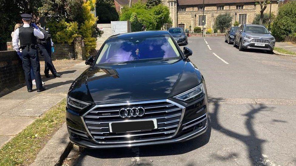 An Audi parked on the street with police officers standing nearby