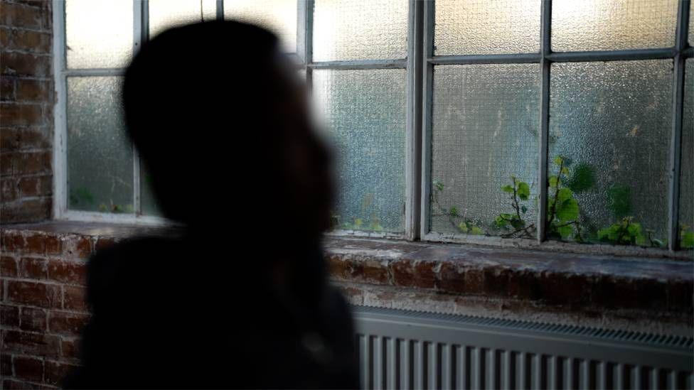 A silhouette of a person is seen in front of a window