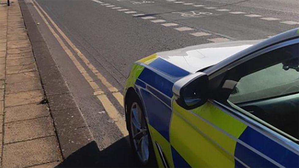 A close-up picture of a police car parked on double yellow lines, with a cycle lane to the right, in Holderness Road, Hull