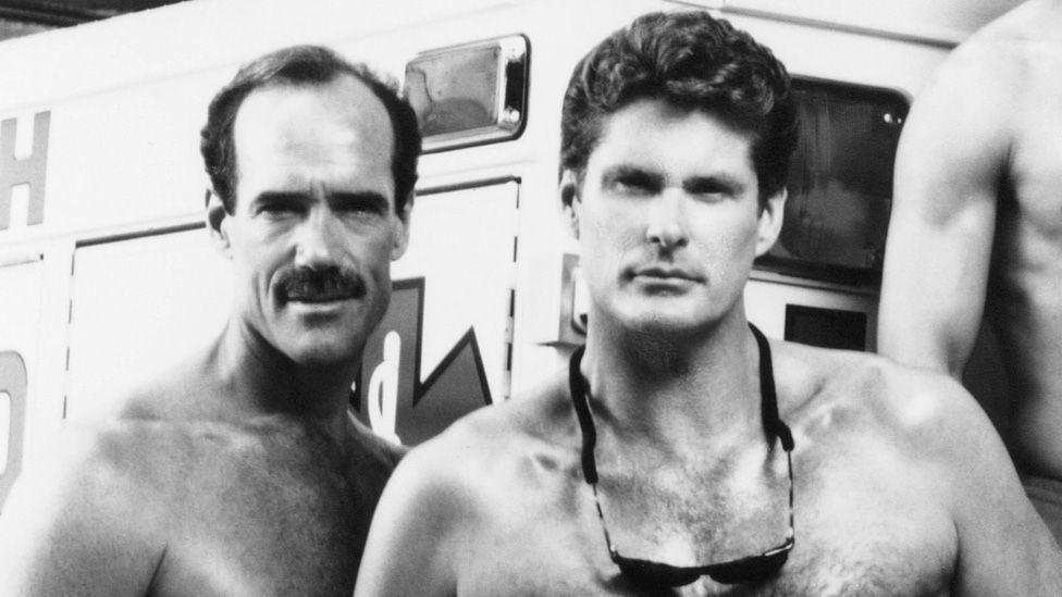 Michael Newman and David Hasselhoff standing together bare-chested on Baywatch