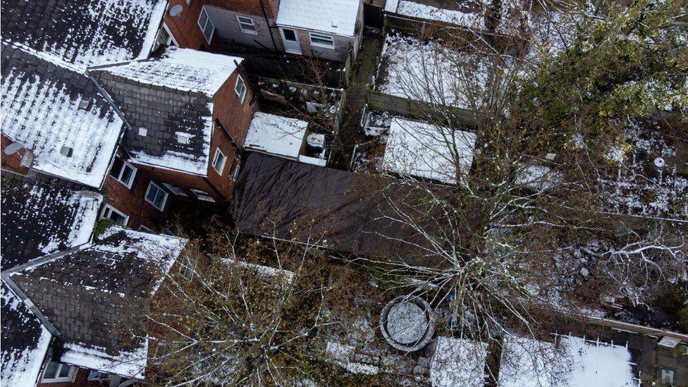 An aerial view of gardens, with the garden in which Abiyah was found covered over by black tarpaulin