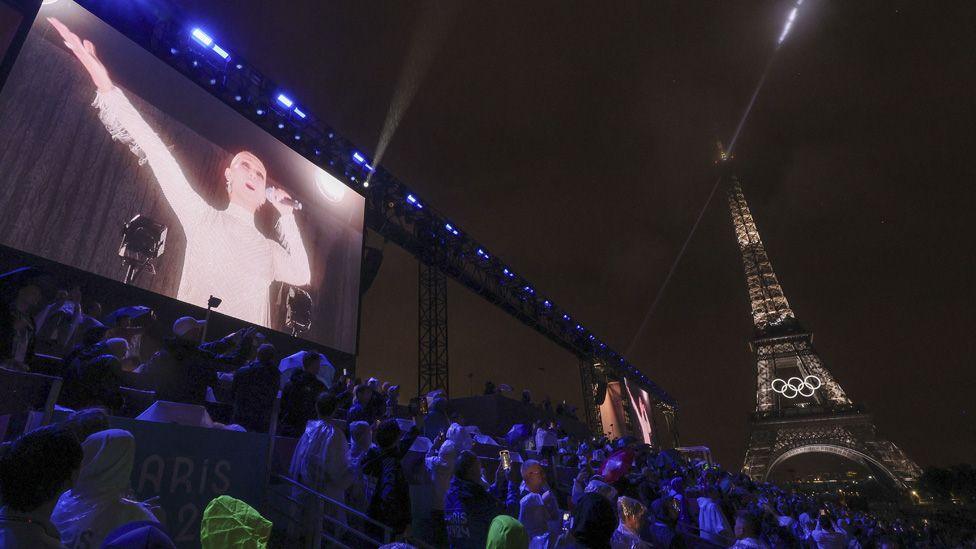 Celine Dion seen on a big screen next to the Eiffel Tower