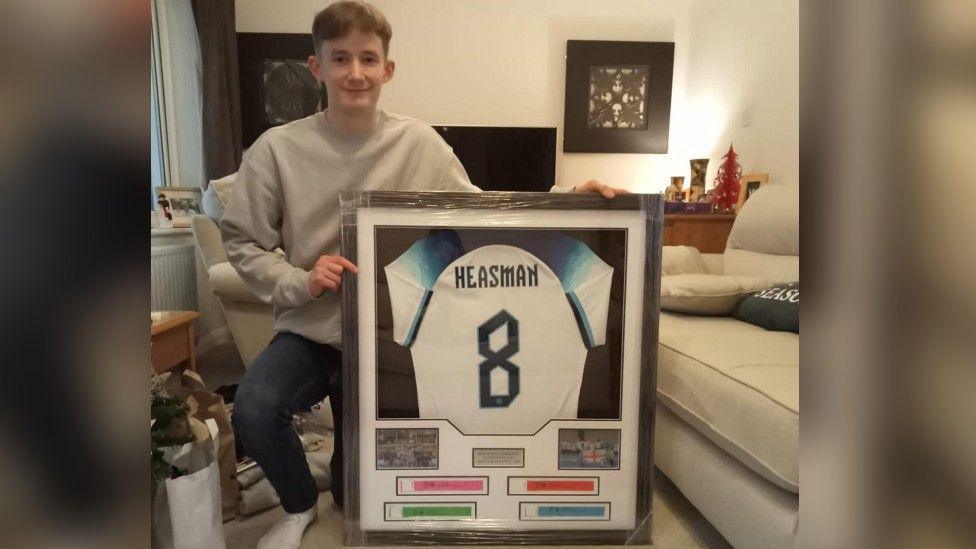 Jake Heasman poses with his England shirt in a frame 