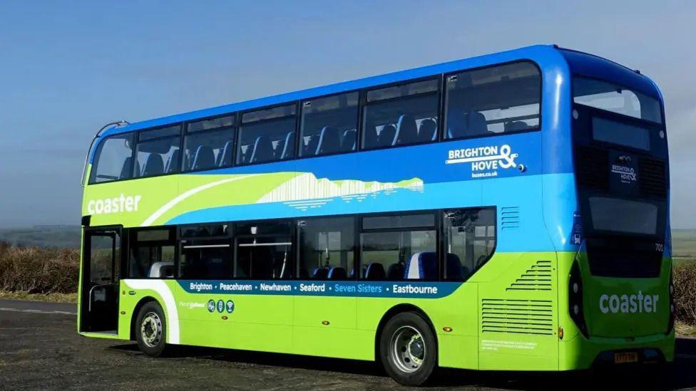 A blue and green double-decker bus parked on a roadside