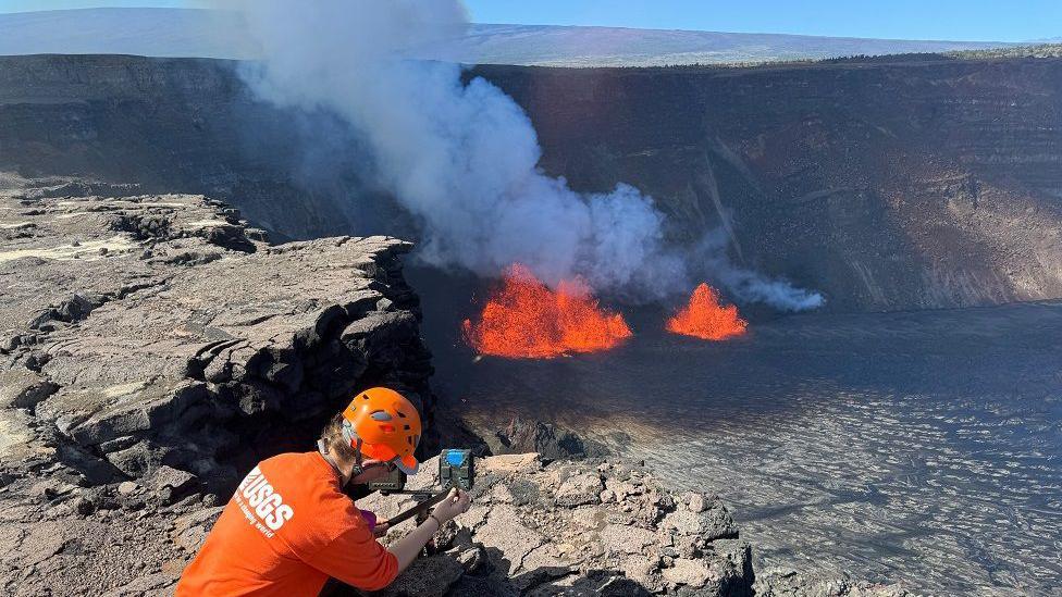 A U.S. Geological Survey Hawaiian Volcano Observatory geologist checks a webcam located on the rim of the caldera