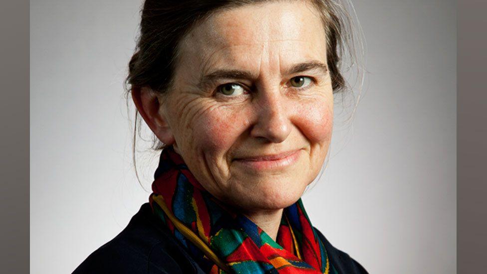 Prof Amy Erickson wearing a brightly coloured scarf and dark top looking towards the camera