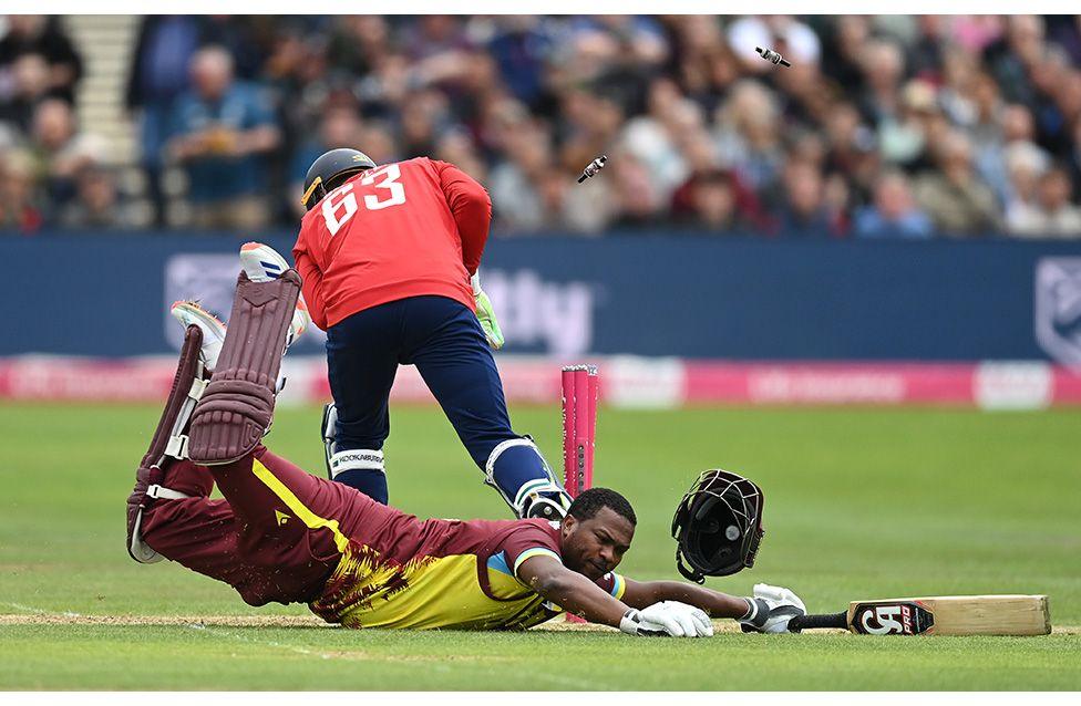 West Indies batsman Johnson Charles dives to make his ground, loosing his helmet in the process as Jos Buttler whips the bails off in the game between England and the West Indies. Photo by Gareth Copley