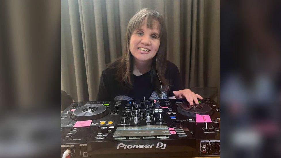 Ashleigh Crowley playing on some DJ decks and smiling