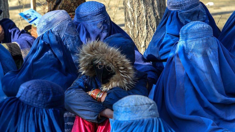 Afghan women wait to receive aid packages in Kabul