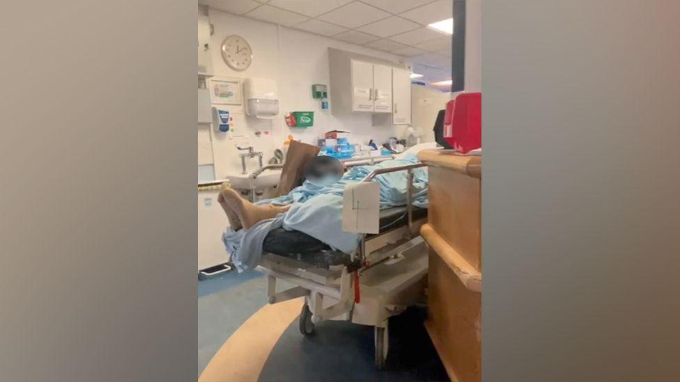 A patient lies on a trolley in the corridor of A&E at the Royal Sussex County Hospital 