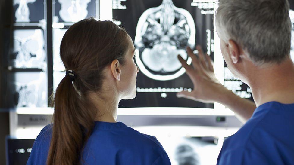 Medical staff view a brain scan on a screen