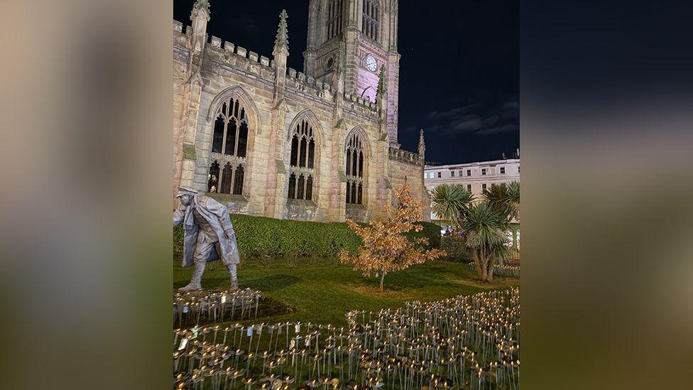 Hundreds of steel flowers in the garden of Liverpool's St Luke's Bombed Out Church as the sun sets.