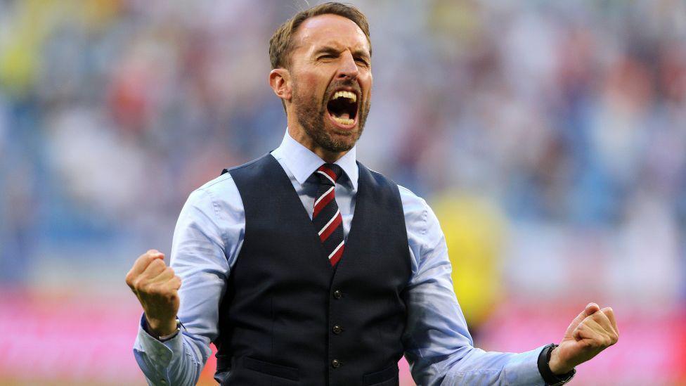 Sir Gareth Southgate celebrating. He is wearing a waistcoat and tie, and is clenching his firsts and has his eyes closed and mouth open. 