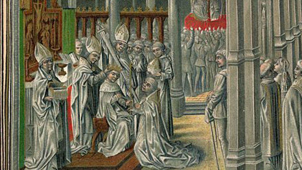 A close-up of a medieval-style image showing Henry IV being crowned. Everyone in the drawing is dressed in white, including the king who is seated. One of a number of bishops in their peaked mitre headgear is placing a gold crown on his head, another is kneeing before him handing him an orb. On the right are men watching the event.
