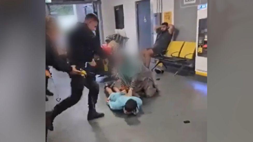 A screenshot of the video where a GMP officer kicks the man on the head at Manchester Airport