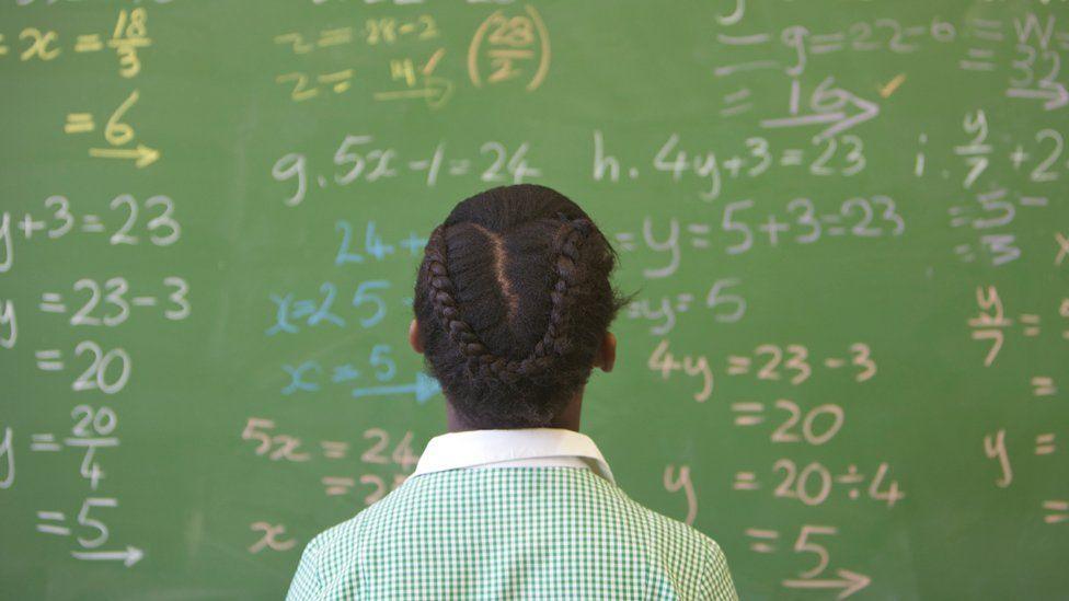 A girl in uniform KwaZulu Natal looking a maths equations on a board at school, South Africa