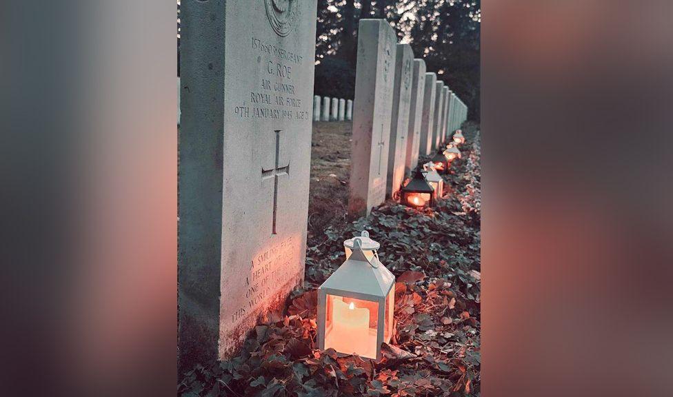 A grave stone with a candle light next to it 