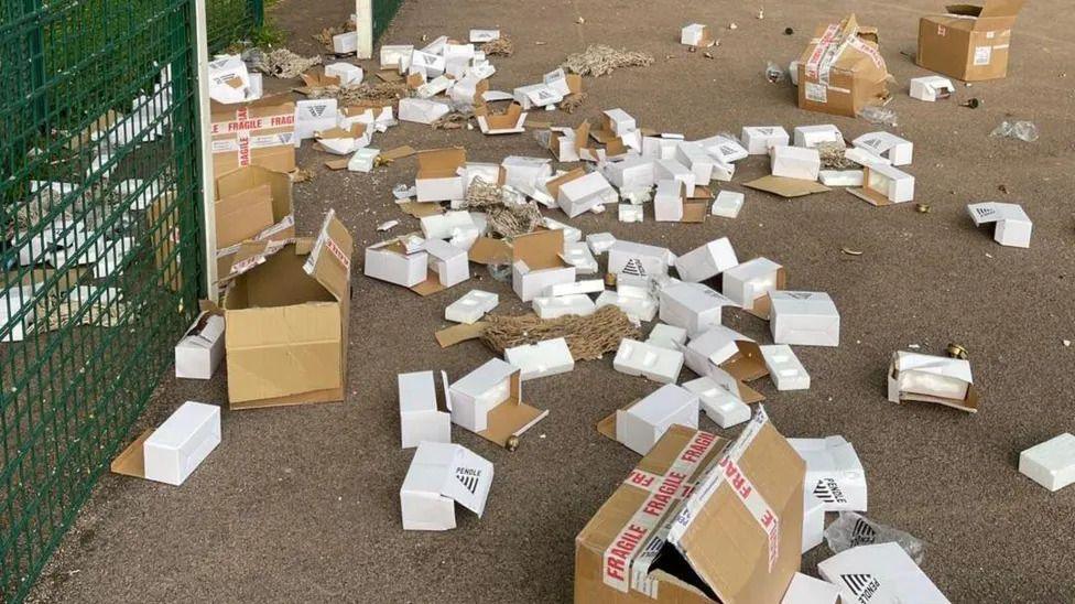 Boxes strewn across a concrete basketball court