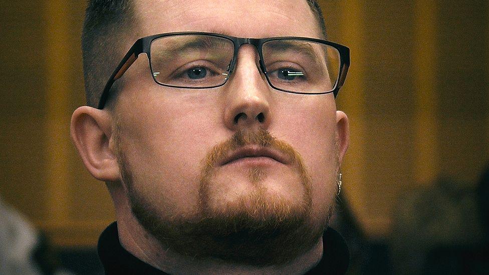 David Barnes in court. He is looking to the side of the camera with his chin lifted up. He has short, cropped hair and a goatee beard. He has dark rimmed glasses and is wearing an earring.