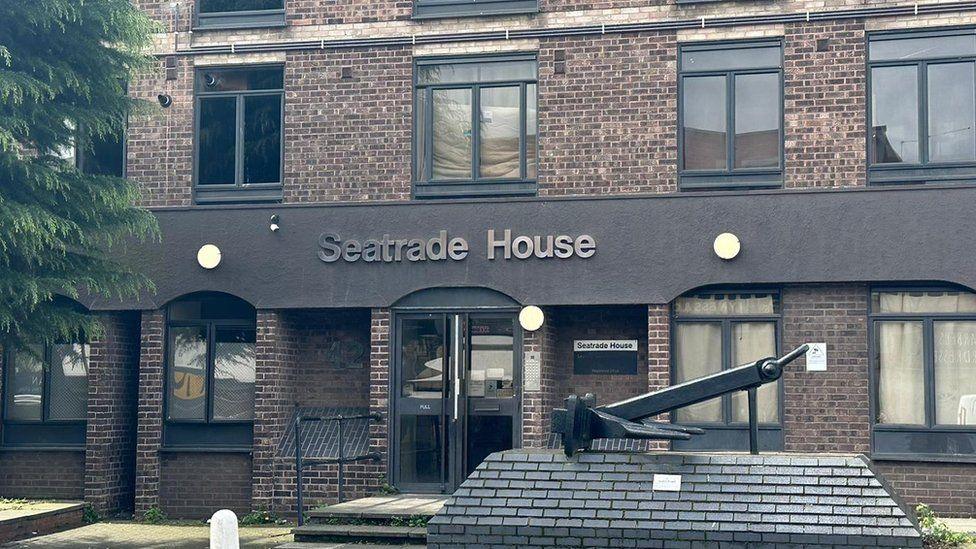 The front of Seatrade House in Colchester. It is made of brown bricks and has lots of windows. There is a brown panel across the middle that has the lettering "Seatrade House". Two-stories of the building are in vision, but it appears there are more above.