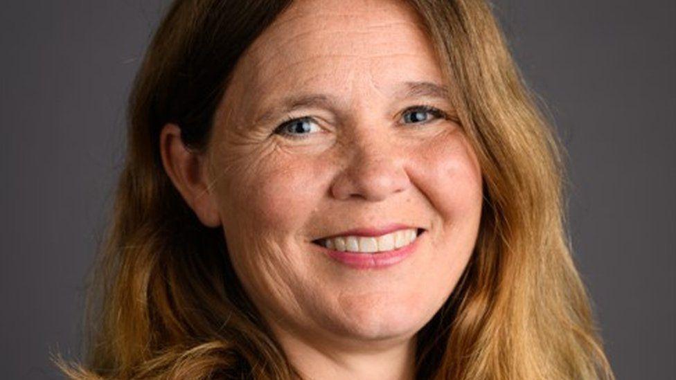 Headshot of Vikki Slade who has long brown hair and is smiling at the camera