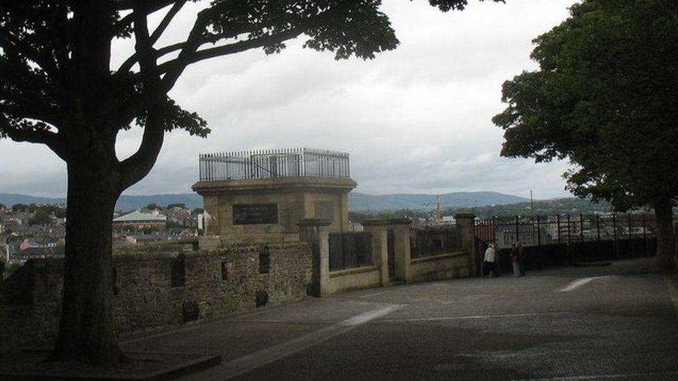 wlakers plinth on the walls of derry, a stone stucture that previously house a tall statue. the city's bogside can be seen in the background