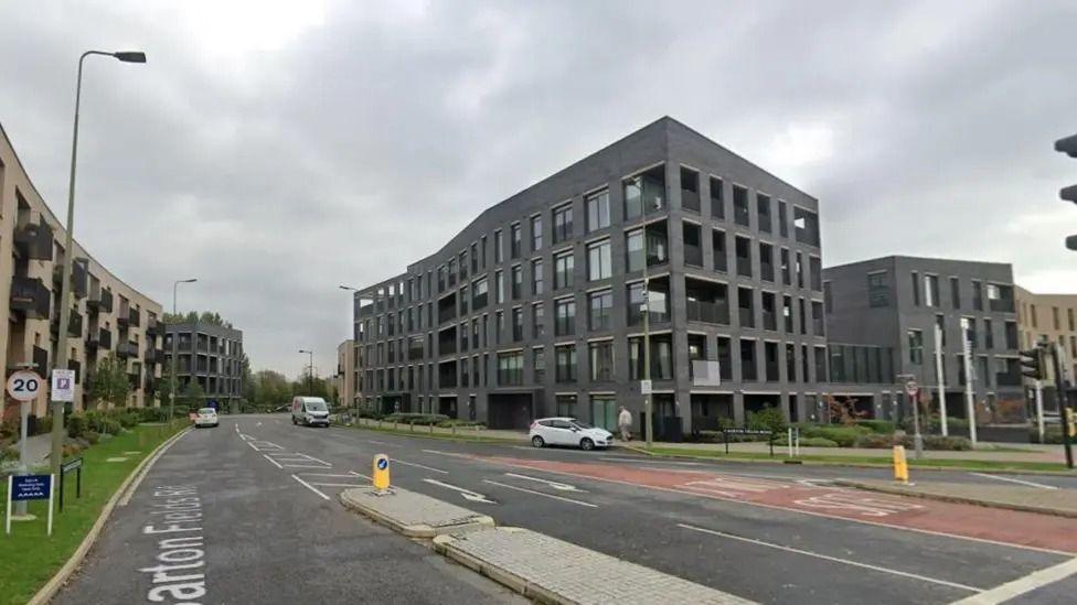 Several grey buildings stand in Barton Park in Oxford under grey clouds