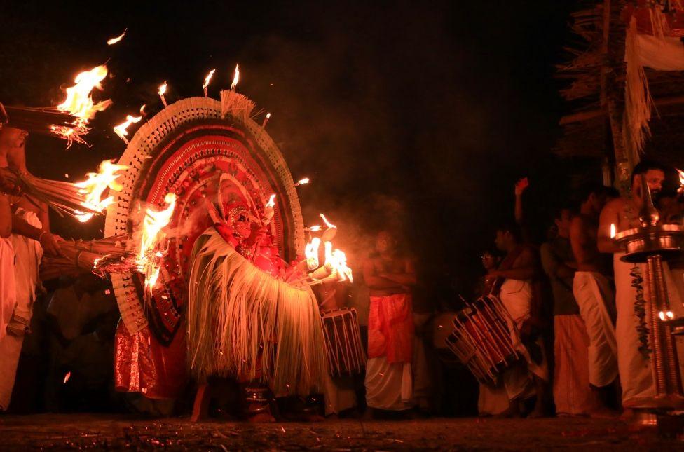 A performer is surrounded by people holding flame-lit torches