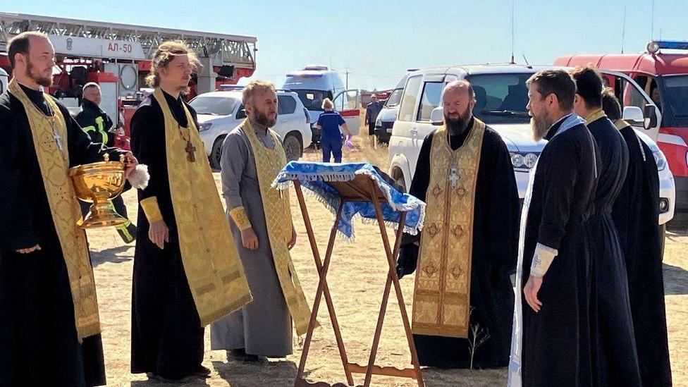 Russian Orthodox clergymen conduct a service around the Unburnt Bush icon, which is considered by Christians in Russia as a talisman against fire, near the accident site at the Proletarsk fuel depot that caught fire following a reported Ukraine's drone attack in the course of Ukraine-Russia conflict, in the Rostov region