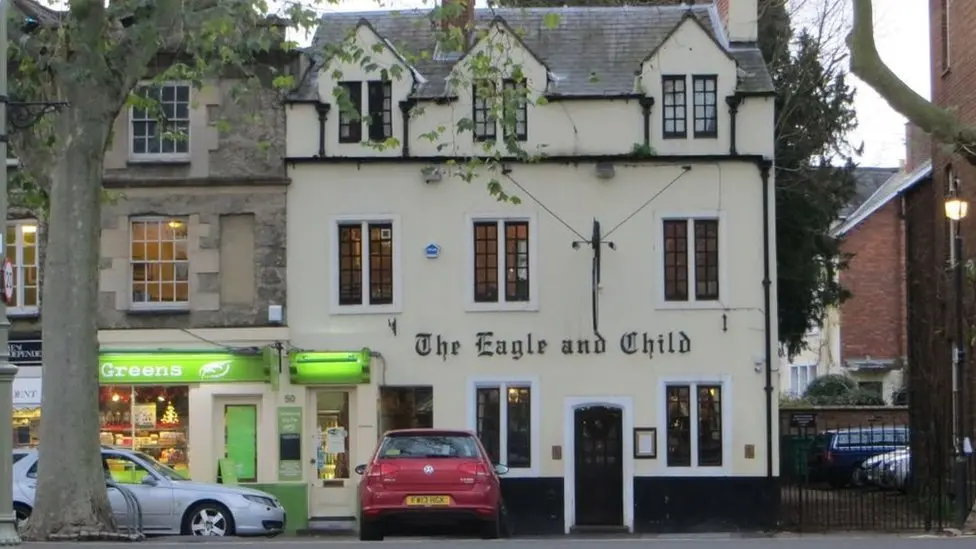 The three-storey Eagle and Child building in St Giles' in Oxford. It is a cream-coloured building and has a red car parked in front of it