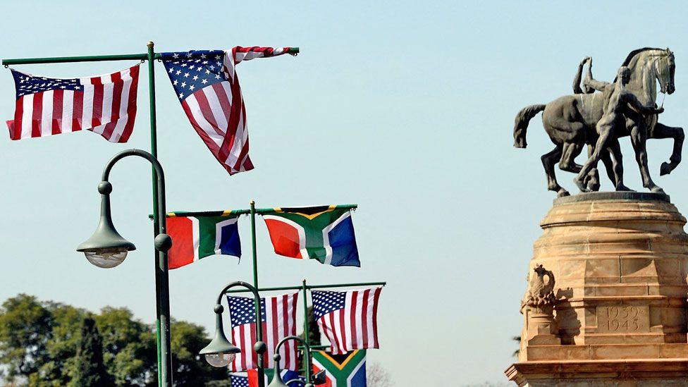 South African and American flags flutter from flag poles by the Union Buildings in South Africa's capital, Pretoria. To the left a monument with a horse marks the dates of World War II.