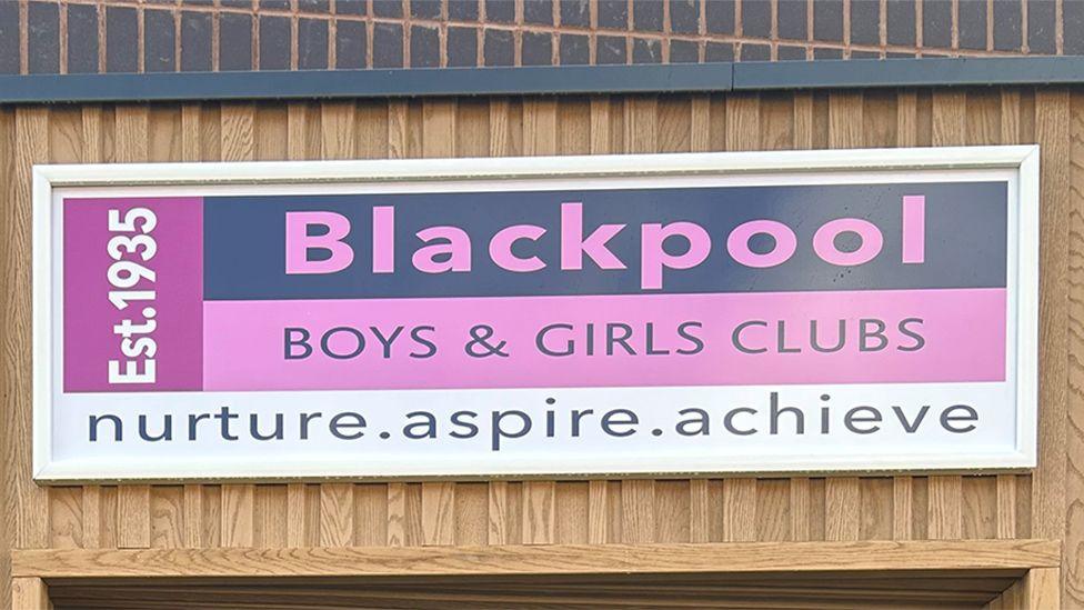 A pink sign saying 'Blackpool Boys and Girls Clubs nurture inspire achieve'