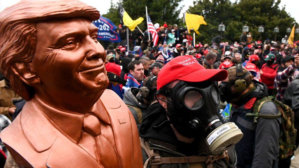  A supporter of US President Donald Trump wears a gas mask and holds a bust of him after he and hundreds of others stormed stormed the Capitol building on January 6, 2021 in Washington, DC, US