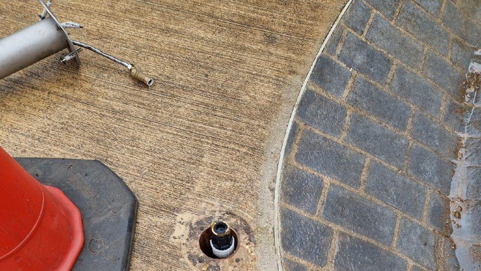 Close up of a piece of metal equipment which has been ripped from its ground fitting