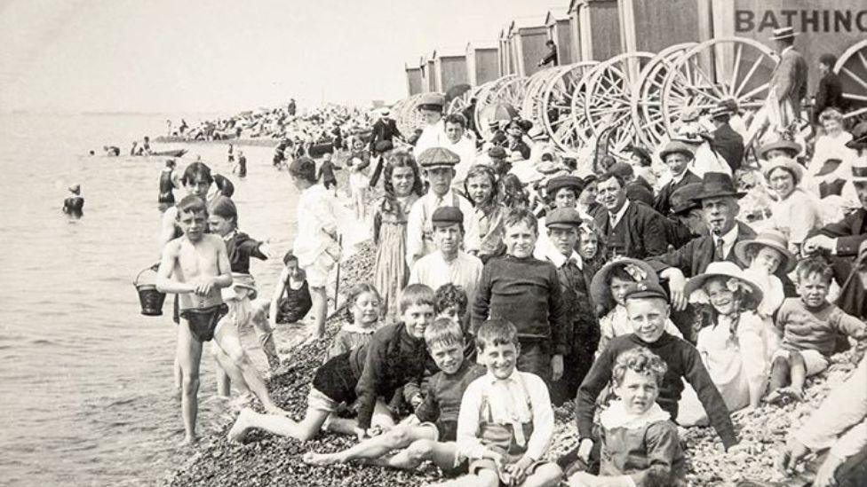 A black and white image of a large group of children on Brighton beach. 