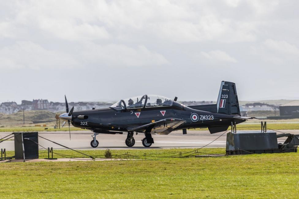 A Beechcraft Texan T1 aircraft seen taxiing to runway to provide basic flying training at RAF Valley. The plane has two seats one in front of the other and is black