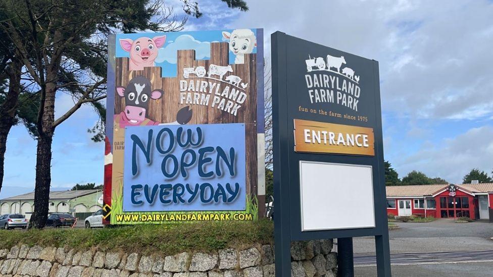 The entrance to Dairyland. A stone wall can be seen with two signs, one saying "Entrance" and the other saying "Now open every day"