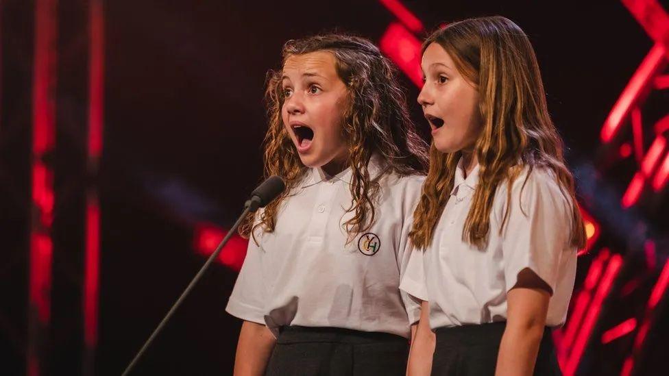 Two girls sing on stage