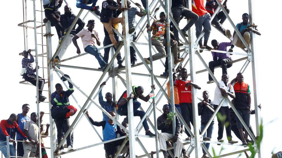 Mourners stand on a tower to see events at the Jomo Kenyatta Stadium in Kisumu.
