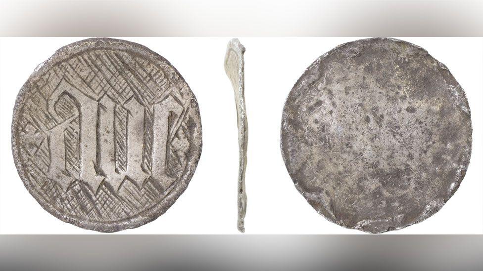 Three views of a silver disc, probably from a late medieval hollow reliquary or box pendant. On its front is etched the Latin word ave and a cross hatching design surrounds the word. Its back is plain and there is a thin side view