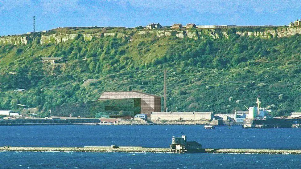 An artist's impression of how the plant will look in the landscape, with the harbour in the foreground and the cliffs of Portland rising up directly behind. The image shows the tall chimney from the plant appears to be about half the height of the cliff.