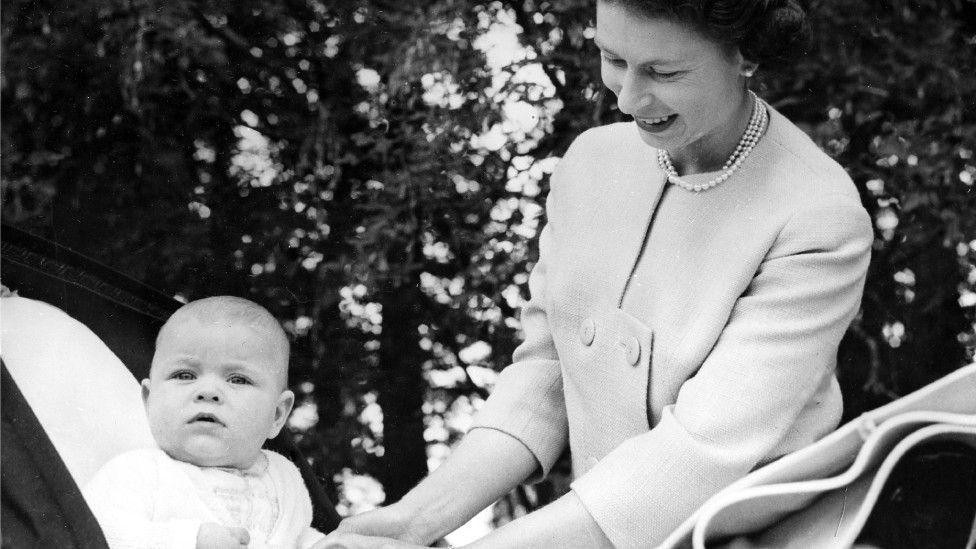 Queen Elizabeth II tends to Prince Andrew in a pram
