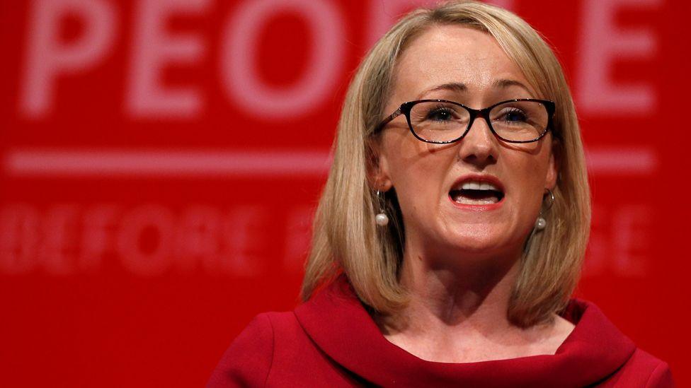 Rebecca Long-Bailey, with black glasses and shoulder-length blonde hair and wearing a red dress, speaks at the Labour party annual conference in Brighton