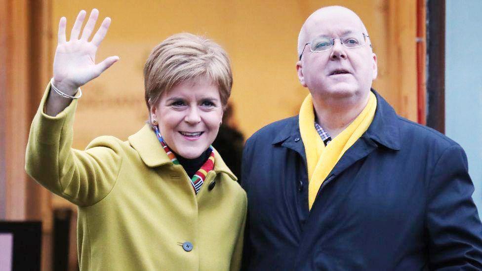 Nicola Sturgeon and Peter Murrell standing side by side in overcoats.